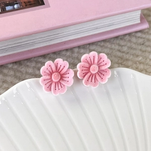 Close-up of pink flocked cherry blossom studs on a decorative white shell tray
