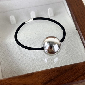 Vue macro d'un élastique à cheveux avec boule métallique argentée au fini poli miroir