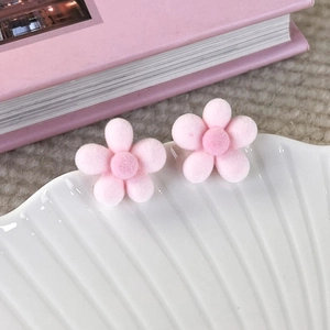 Close-up of pink flocked cherry blossom stud earrings on a white scallop shell tray