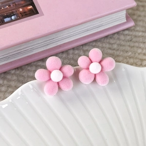 Macro detail of soft flocked pink cherry blossom earrings on white shell plate