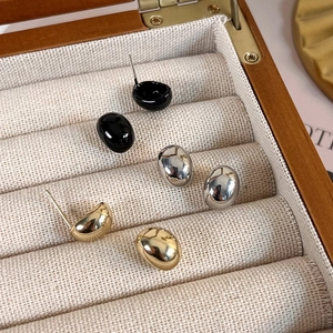 Minimalist bean-shaped stud earrings set in polished gold, silver, and black metal finishes