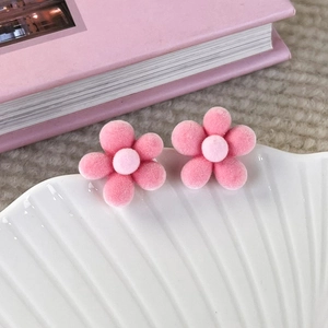 Close-up of pink velvet flower earrings on a decorative tray with soft petals