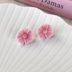 Close-up of pink flocked cherry blossom stud earrings with soft velvet petal texture