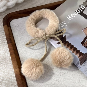 Dettaglio di un elastico per capelli in peluche crema con pompon in ecopelliccia