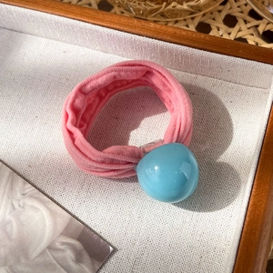 Vue macro d'un chouchou en velours rose avec un ornement sphérique bleu clair poli
