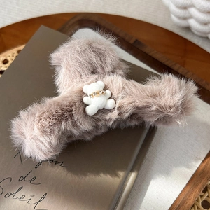 Detailaufnahme der flauschigen Haarklammer mit süßem weißen Teddybären und Goldhalsband