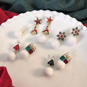 Set di orecchini natalizi con ciondoli a fiocco di neve e pompon su un vassoio festivo