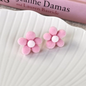 Detailed close-up of pink flocked cherry blossom stud earrings on a white shell tray