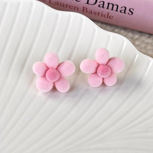Close-up of pink flocked cherry blossom stud earrings on a white ceramic wave tray