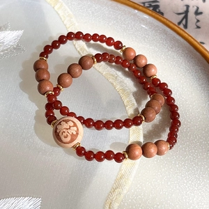 Détail d'un bracelet en agate rouge et bois avec un pendentif chinois porte-bonheur