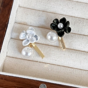 Asymmetric black and white gardenia earrings with elegant pearls on velvet jewelry box