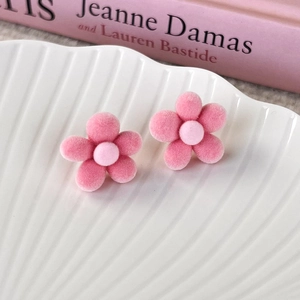 Close-up of sweet pink flocked cherry blossom stud earrings on a white shell plate