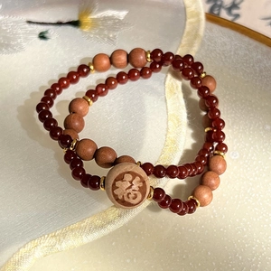 Détail macro de perles en agate rouge et bois avec breloque gravée du caractère Fu chinois