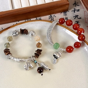 Detail of ethnic bracelets with elephant and cat charms in a ceramic bowl
