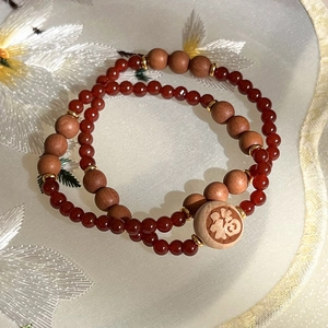 Gros plan de perles d'agate double couche avec charme en bois Fu et accents dorés