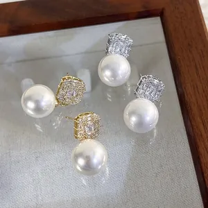 French zircon pearl studs in gold and silver finish on a wooden glass jewelry tray