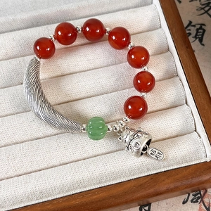 Detailed shot of ethnic beaded bracelet with red agate beads and lucky cat bell charm