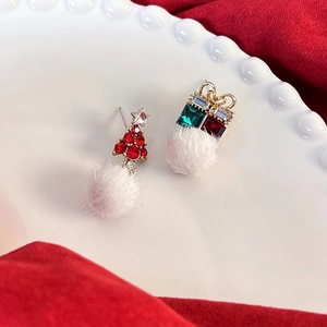 Dettaglio di orecchini natalizi con albero rosso, scatola regalo e pompon bianchi