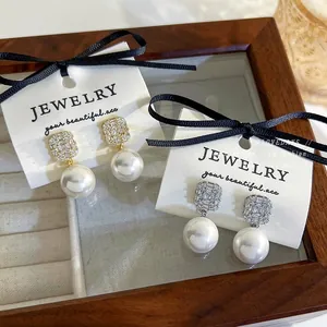Detail view of zircon crystal pearl earrings in gold and silver finish on display card