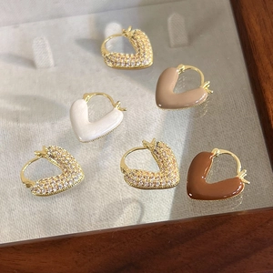 Gros plan de boucles d'oreilles cœur dorées avec zircons et détails en émail multicolores