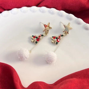 Dettaglio di orecchini ad albero di Natale con stelle dorate e pompon bianchi