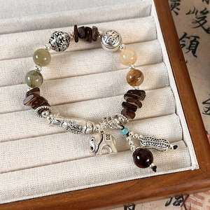 Detail of ethnic beaded bracelet featuring silver elephant charm and green stone beads