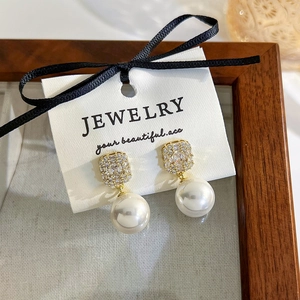 Close-up of vintage pearl drop earrings with square zircon gold plating on a jewelry card