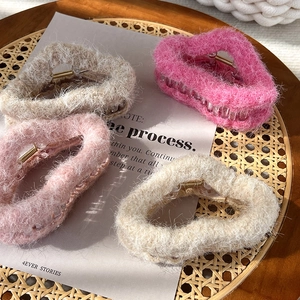 Plüsch-Haarklammern in Creme, Rosa und Kaffeetönen auf einem rustikalen Tablett
