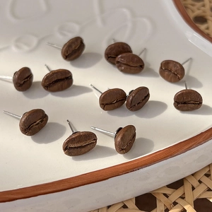 Artistic coffee bean stud earrings in a scattered arrangement on a white tray