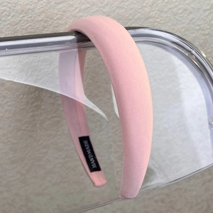 Detailed close-up of pink handmade sponge headband with a black woven handmade label