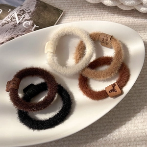 Five-piece plush elastic hair scrunchies set in earth tones with leather logo labels