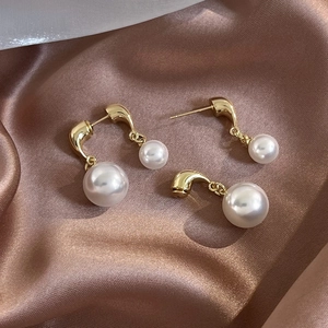 French vintage style pearl earrings with golden J-shaped metal hook on silk background