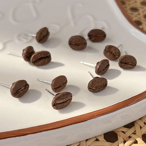 Macro detail of coffee bean stud earrings showing realistic texture in a ceramic dish