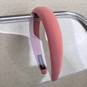 Detail shot of coral pink sponge padded headband with a woven HAND MADE textile label
