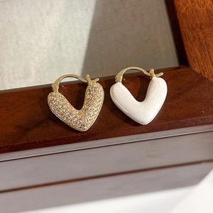 Détail de boucles d'oreilles cœur en V avec placage d'or, zircons et émail