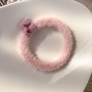 Detailed close-up of a pink plush hair tie featuring a purple butterfly tag decoration