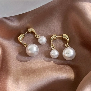 Detailed macro view of French vintage pearl earrings with gold metallic chain on silk fabric