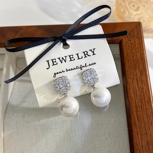 Detail of silver stud earrings with square zircon clusters and round white pearl drops