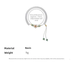 Detail view of flower pendant and jade-like beads on resin bracelet with woven rope