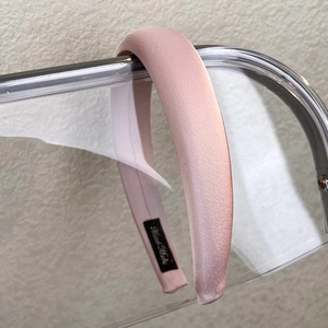 Detail view of pink padded sponge headband with subtle satin sheen on acrylic stand