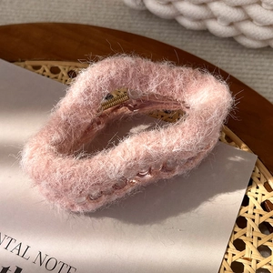 Detail einer rosa Plüsch-Haarklammer mit weicher Textur auf einem Holztablett