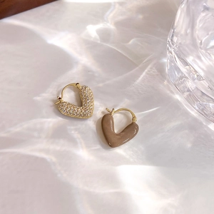 Vue détaillée de boucles d'oreilles cœur dorées avec zircons et émail brun brillant