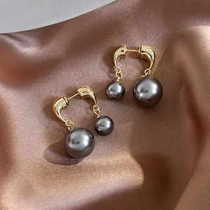 Macro detail of French vintage gold earrings with layered dark grey pearls on silk