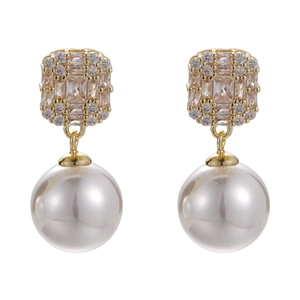 Elegant gold earrings with square zircon studs and large round pearl drops on white background