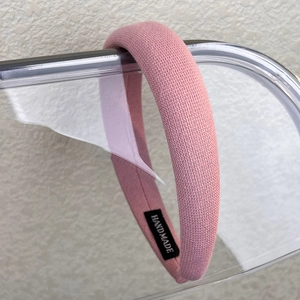 Macro detail of pink knitted headband with honeycomb texture and handmade label