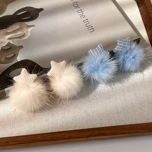 Close-up of plush star earrings in blue and beige with soft faux fur texture details