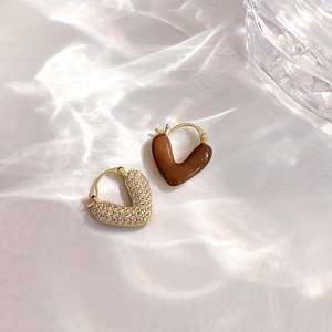 Détail de boucles d'oreilles en cœur plaquées or avec zircone et émail marron