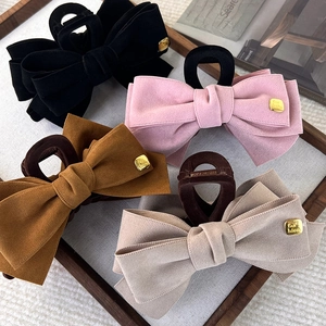 Set of four velvet bow hair claws in black, pink, brown, and beige on a wooden tray
