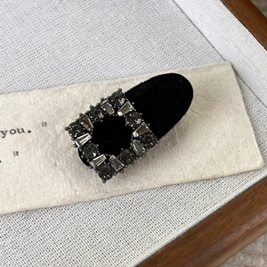 Detail of vintage black velvet hair clip with grey rhinestones on a rustic background