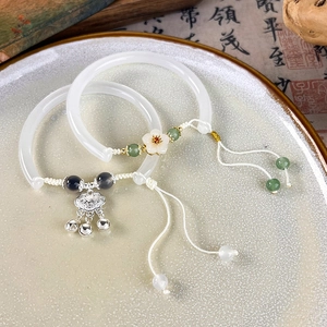 Detail of vintage Chinese flower bracelets with peace lock and tassels on a ceramic plate